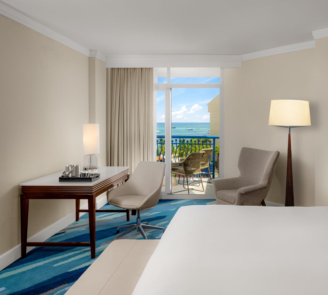 Large Bed, Desk, Armchair and Balcony in a Guest Room with Ocean View