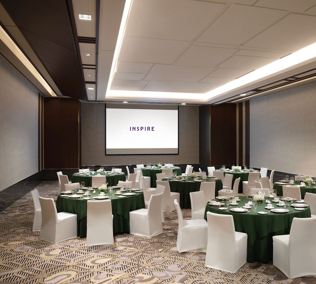 Ruang pertemuan dengan meja bundar dan proyektor dengan logo properti