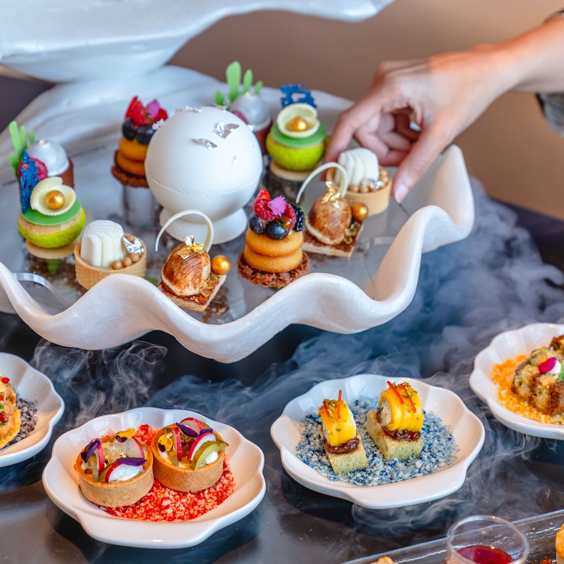 A woman's hand selecting a snack fro a tray on a table at Osmo lounge & bar-transition