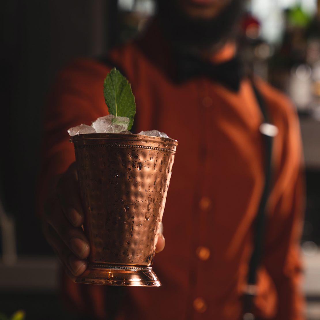 barman care servește un cocktail într-o cupă de cupru
