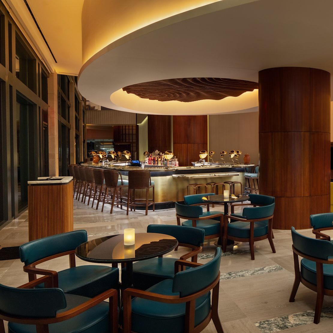 テーブルとバンケットチェアを備えた「アペロ・ホテルのバー&ラウンジエリア」。- 移行