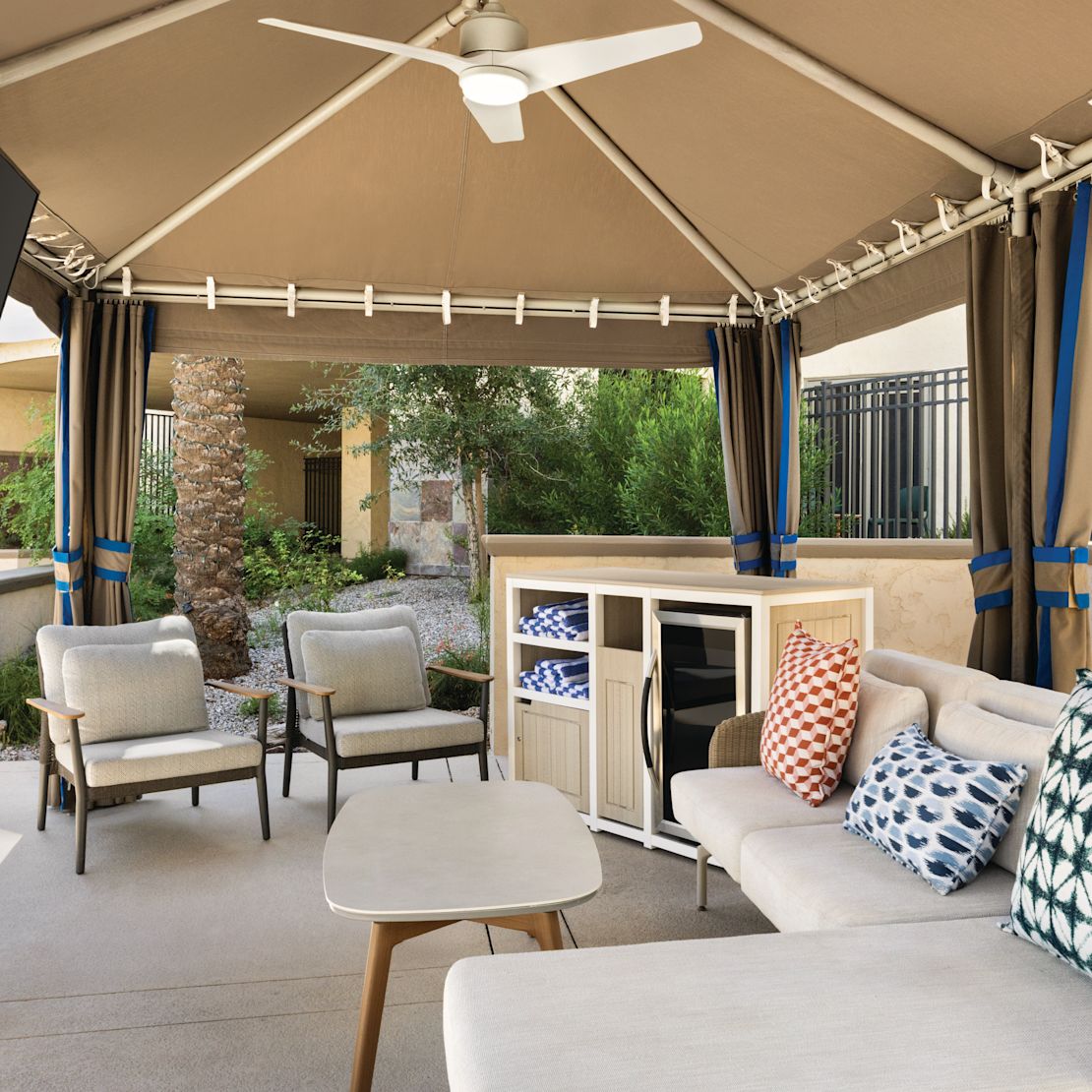 Outdoor cabana with soft seating and a mini fridge.-transition