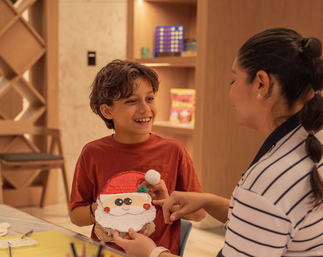Una donna e un ragazzo che si divertono a preparare le decorazioni natalizie al Kids Club - passaggio successivo