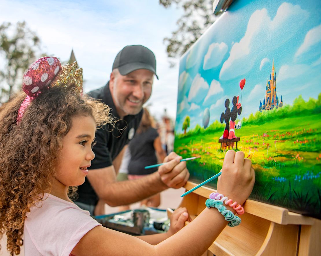little girl  and instructor painting a picture of mickey and mini mouse-transition