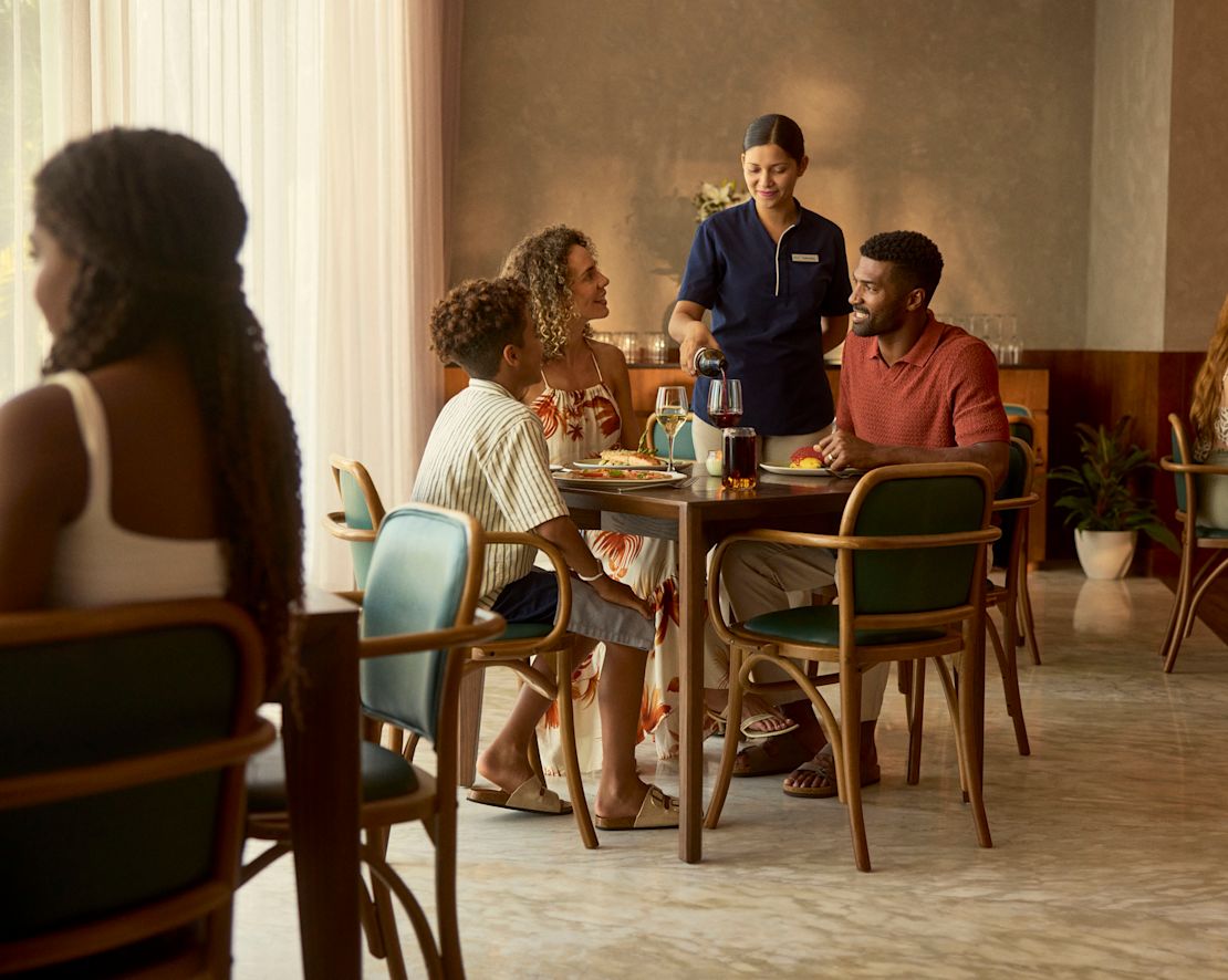 A la madre, al padre y a su hijo se les sirven bebidas por medio de una camarera-transición