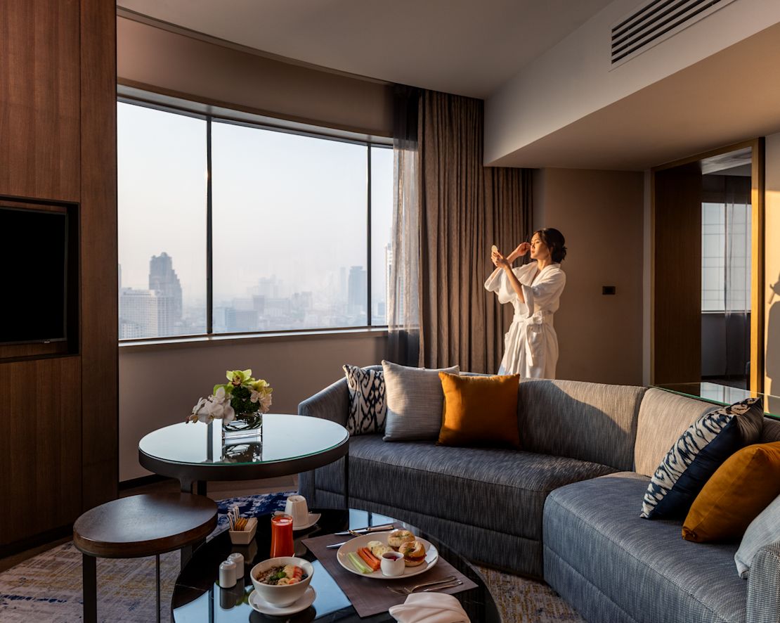 スイートのリビングエリアに立つシティビューの女性
