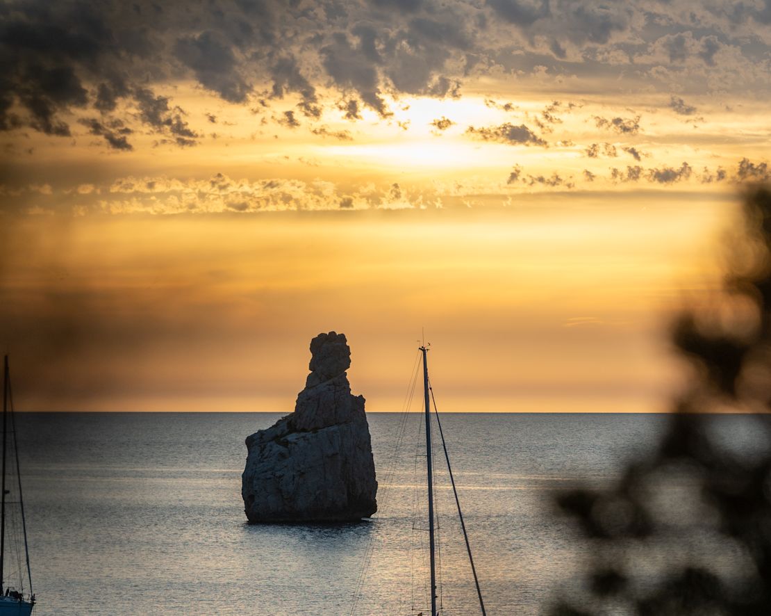 Stockbild eines Boots auf dem Wasser bei Sonnenuntergang für den Club Cala San Miguel-Übergang