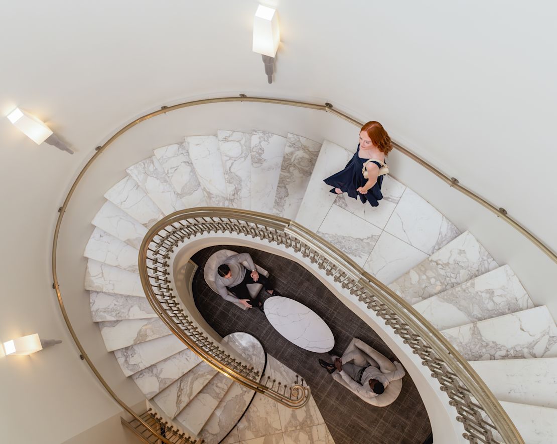 Lobby area with woman descending spiral staircase-transition