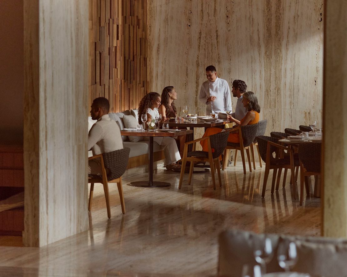 Kock eller servitör pratar med familj som består av far, mor, dotter och mormor-övergång