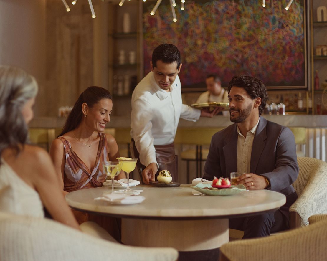 Två kvinnor och en man dricker och efterrätter i Peacock Alley-övergången