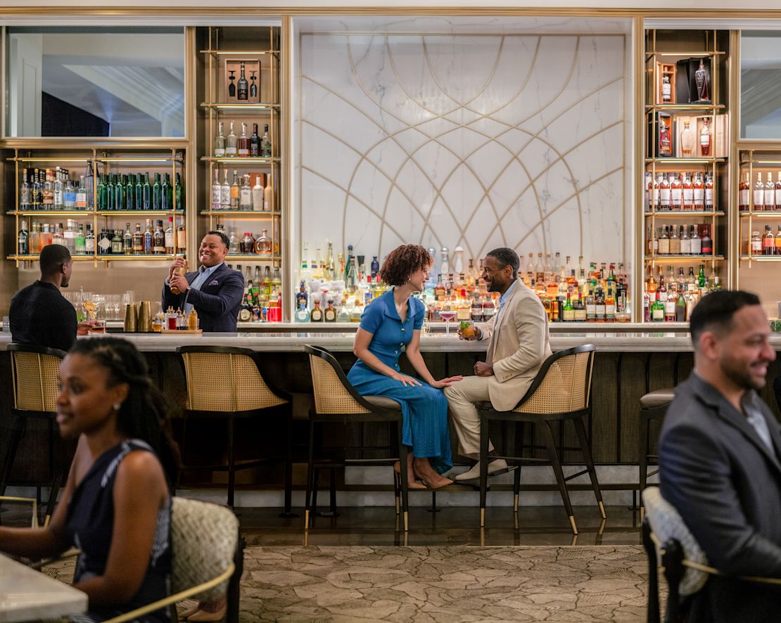 Groupe de personnes dans le bar, dont un couple souriant avec des boissons, prochaine transition