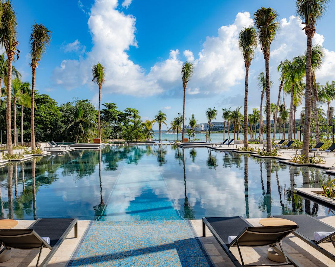 Piscine extérieure avec palmiers et méridiennes, transition