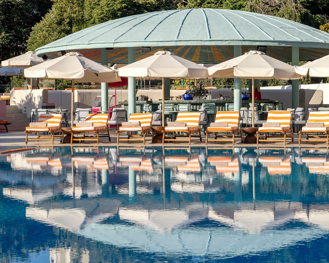 Zonă piscine în aer liber cu scaune lounge sub umbrele-transition