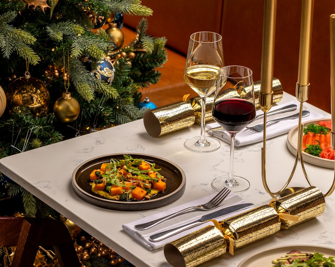 タイバーン・キッチンのクリスマスツリーを背景にした盛り付け料理 - トランション