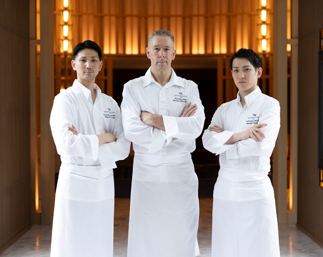 Three chefs standing together wearing white chef's coats.-transition