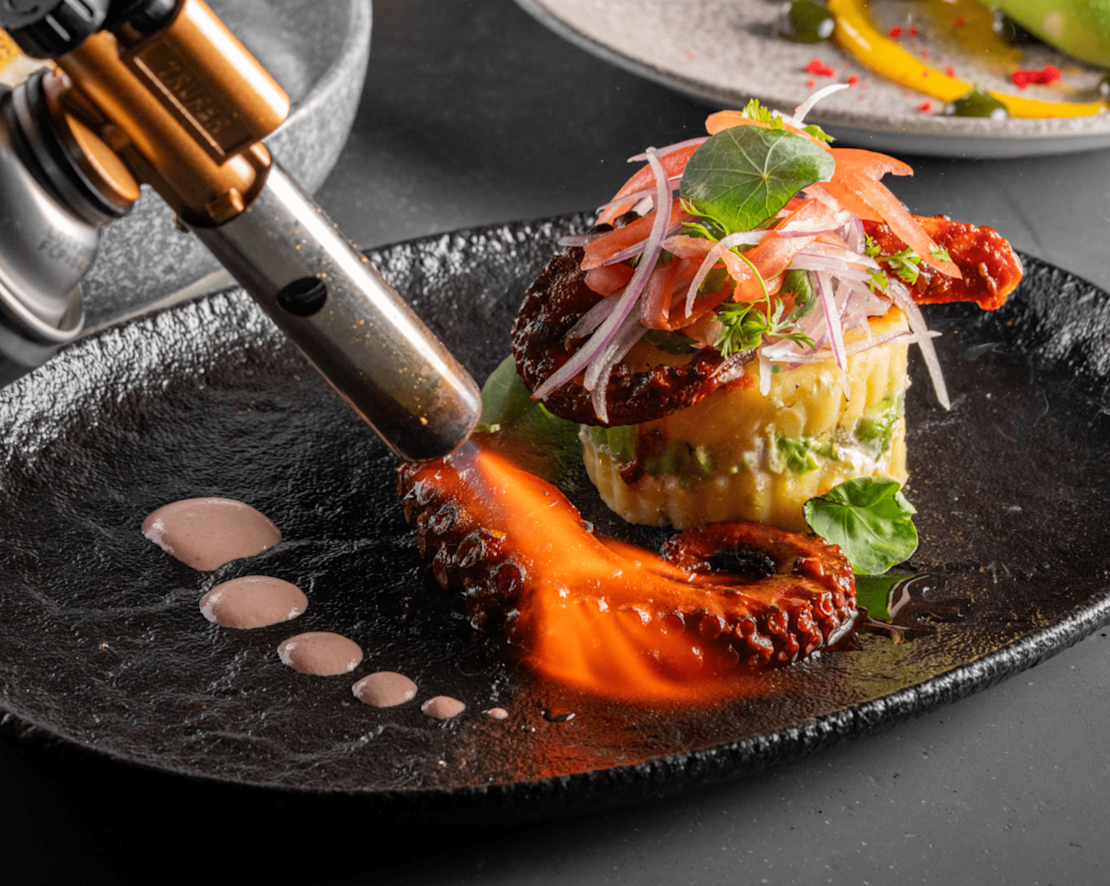 O tocă bucătară aplicată pe o farfurie cu caracatiță la restaurantul Noriku - Tranziție