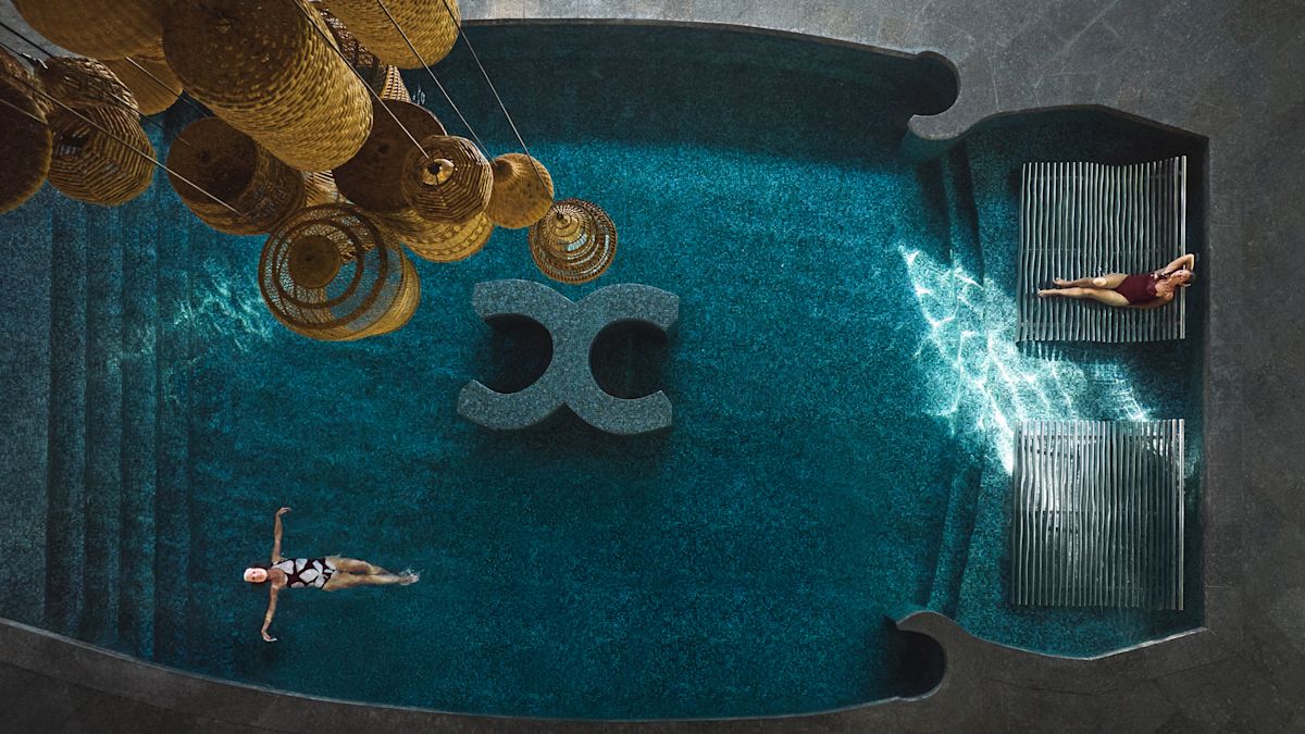 Uitzicht op de vogelvlucht van een vrouw die op haar rug zweeft in het zwembad en ontspant terwijl een andere vrouw in een van de ligstoelen in het zwembad rust