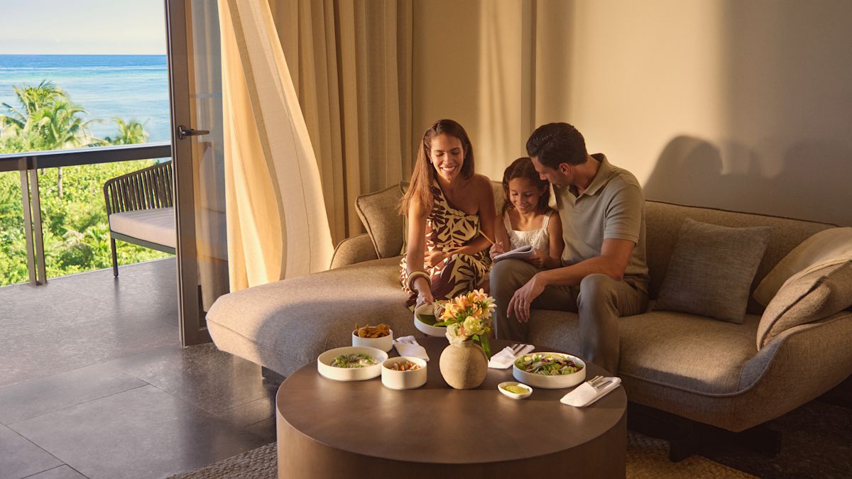 엄마, 아버지, 딸은 스위트에서 샐러드와 가벼운 간식을 즐기고 있으며 딸은 공책을 쓰고 있습니다.