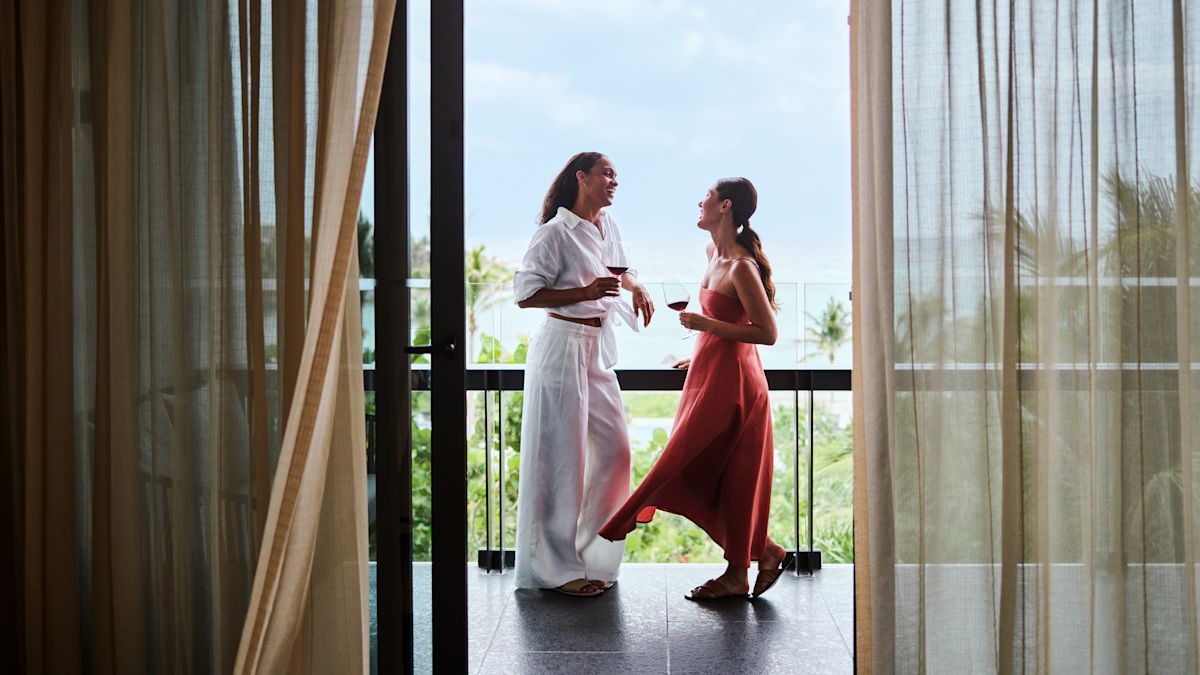 Two women standing on balcony with drinks