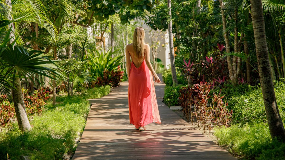 Woman in pink dress walking in spa groundsthrough S