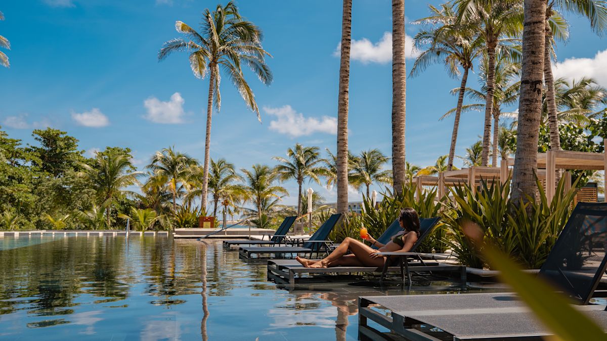 Frau am Swimmingpool mit Cocktail
