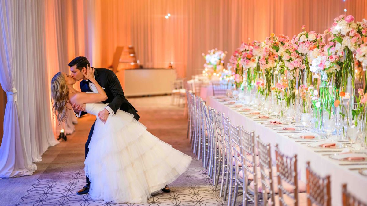 couple kissing on their wedding day in a ballroom setup for a wedding celebration