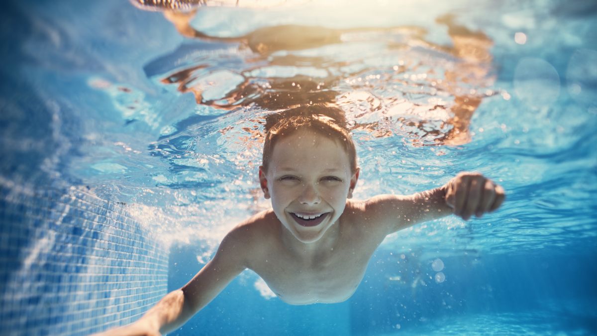 A child smiling and swimming underwater.