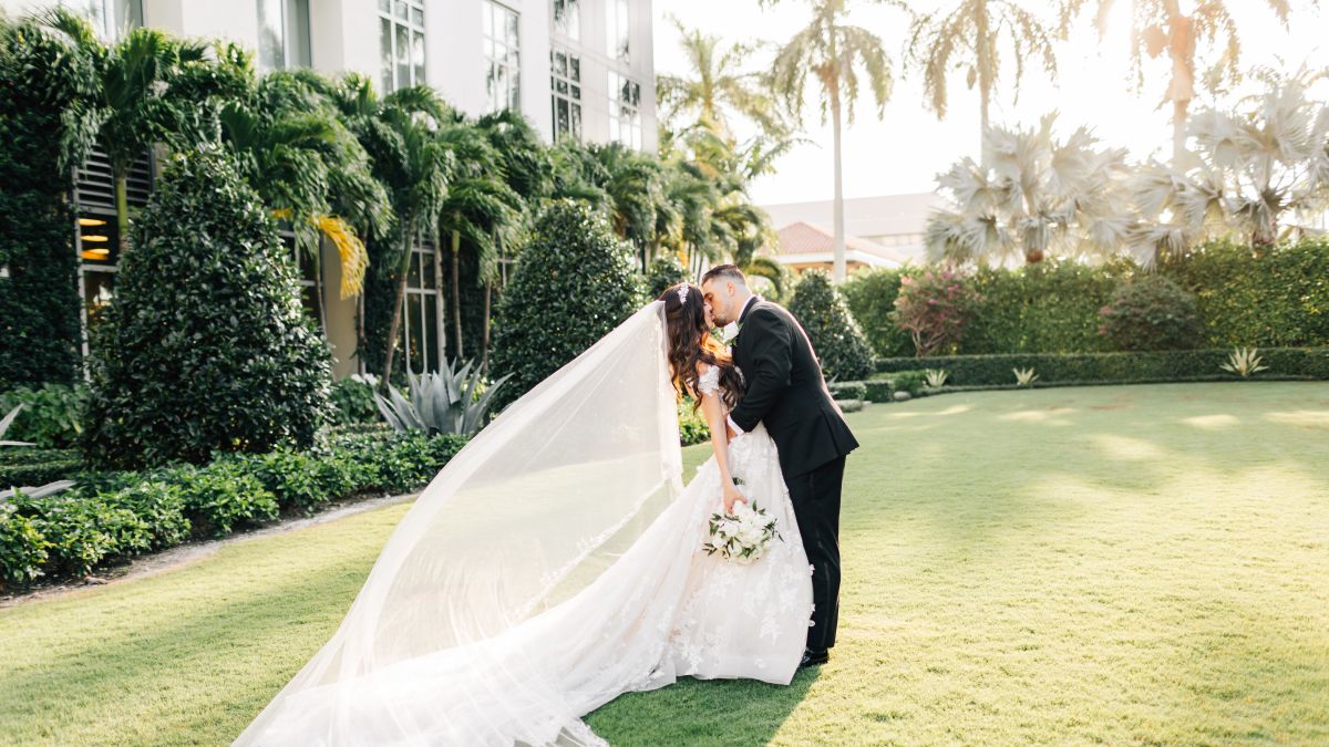 a Newlywed Couple Kissing in a Garden with Palm Trees