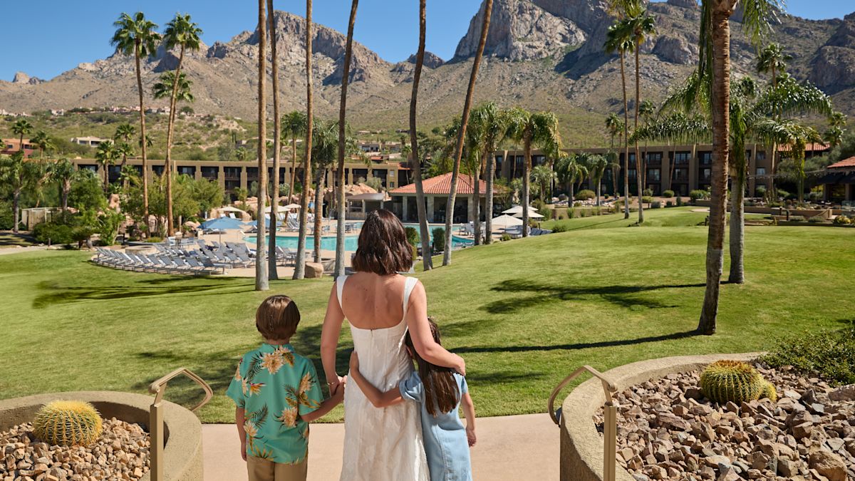 family looking the outdoor pool, palm trees and mountains