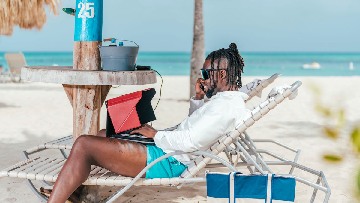 Man working on the beach with laptop and phone