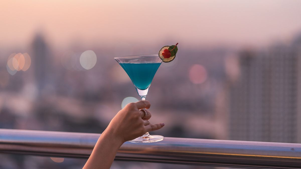 Femeie ținând în mână o sticlă de cocktail la barul treizeci pe acoperiș