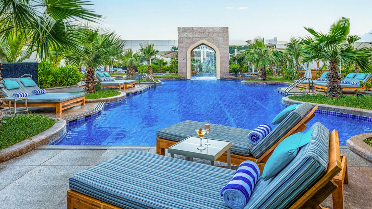 Área de la piscina al aire libre con divanes y palmeras