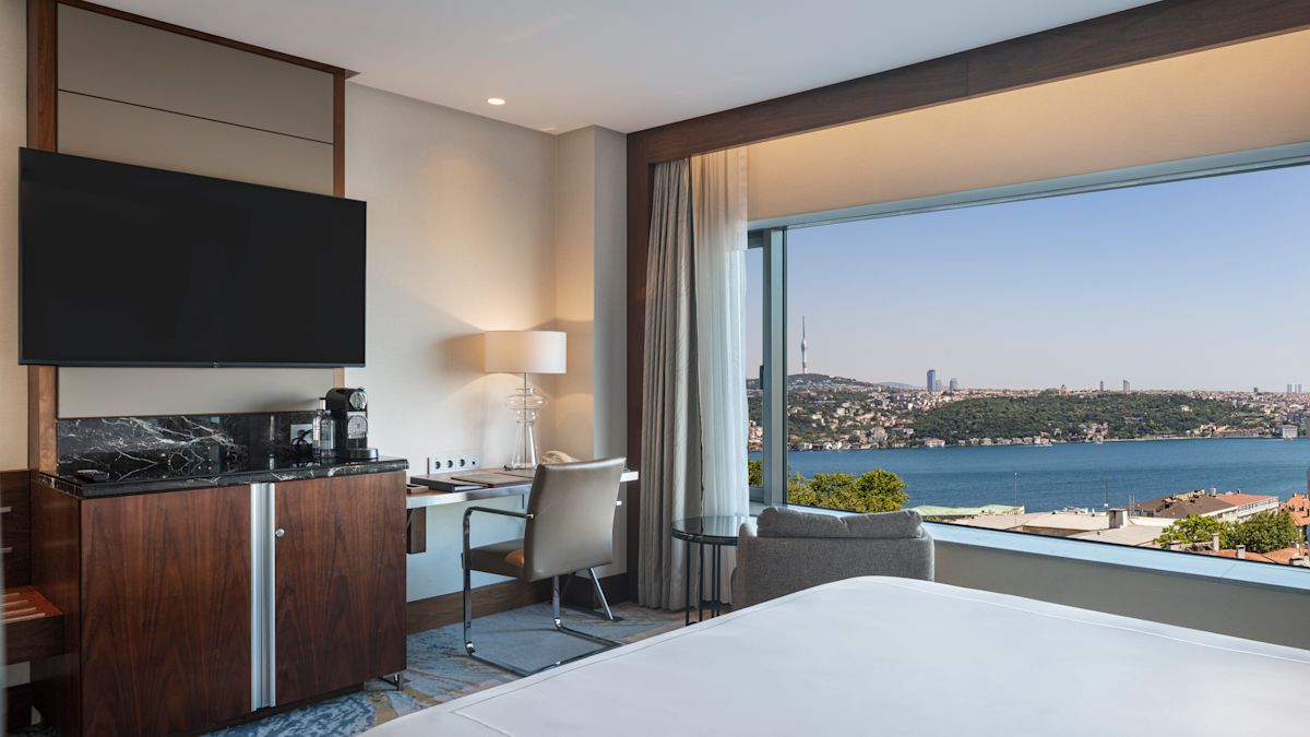 Bed in room with tv, work desk and sea view