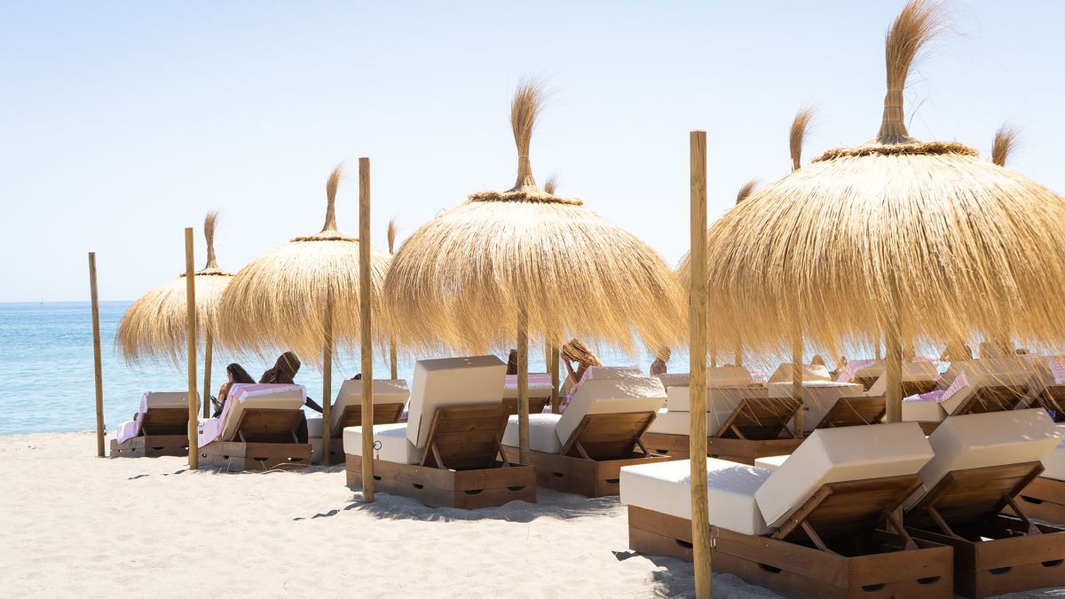 Entspannende Loungesessel unter Sonnenschirmen am Strand