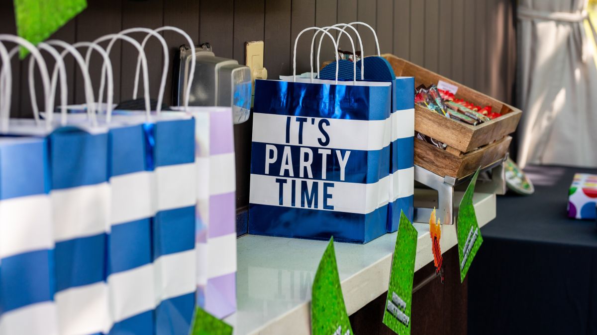 Party bags reading "It's party time!" on a table with birthday decorations.