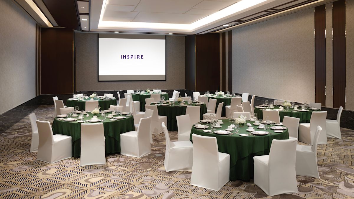 원형 테이블 및 호텔 로고가 있는 프로젝터가 있는 회의실