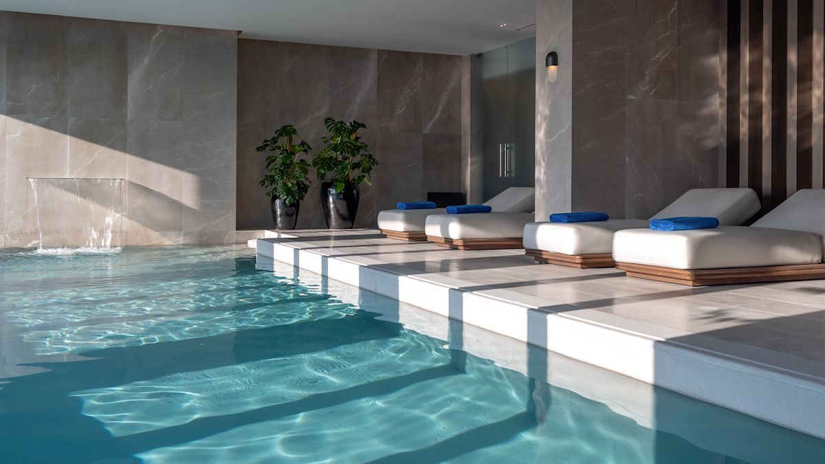 Piscina termale Aurora con quattro lettini e una cascata.