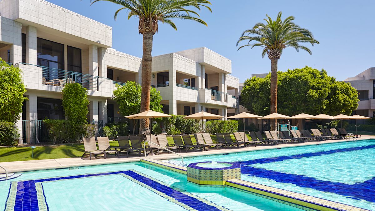 Outdoor Pool Area with Seats under Umbrellas and Palm Trees