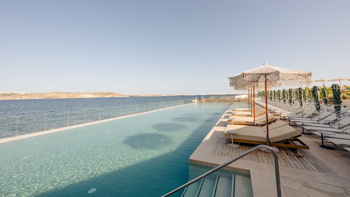 Patio con divanes con vista a la piscina y al mar en un día soleado