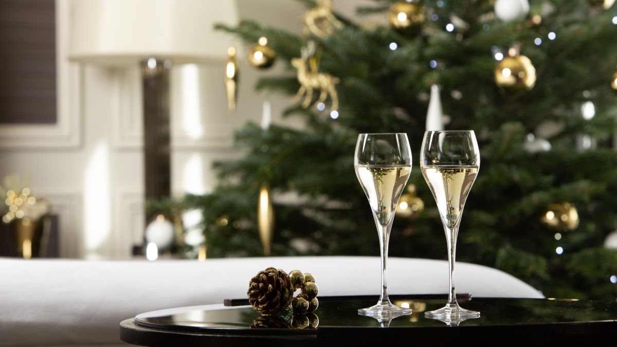 Champagne sitting on table, with christmas tree behind
