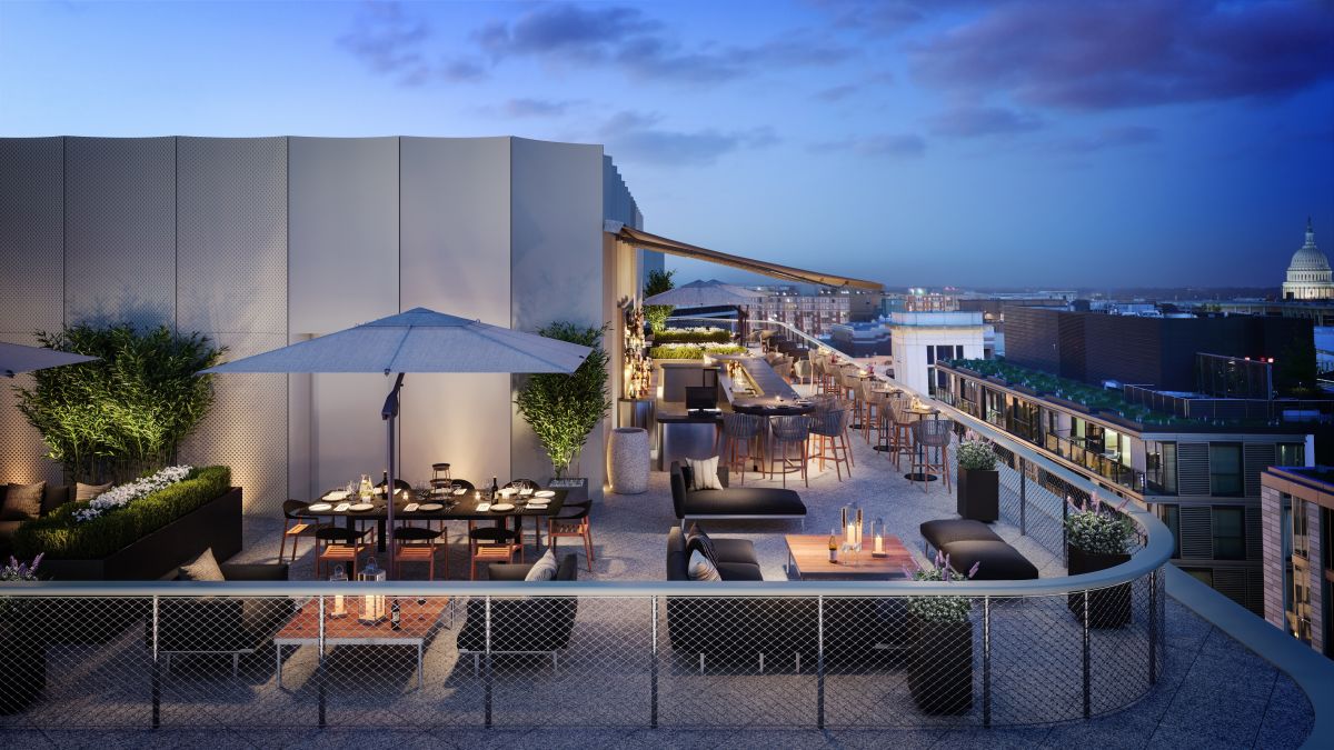View of Rooftop Bar with Dining Tables, Chairs, and Soft Seating at Dusk