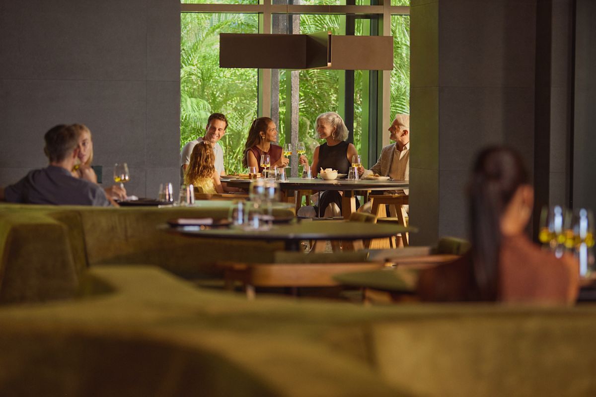 Familie formată din bunic, bunică, tată, mamă și fiică savurând o masă în restaurantul hotelului