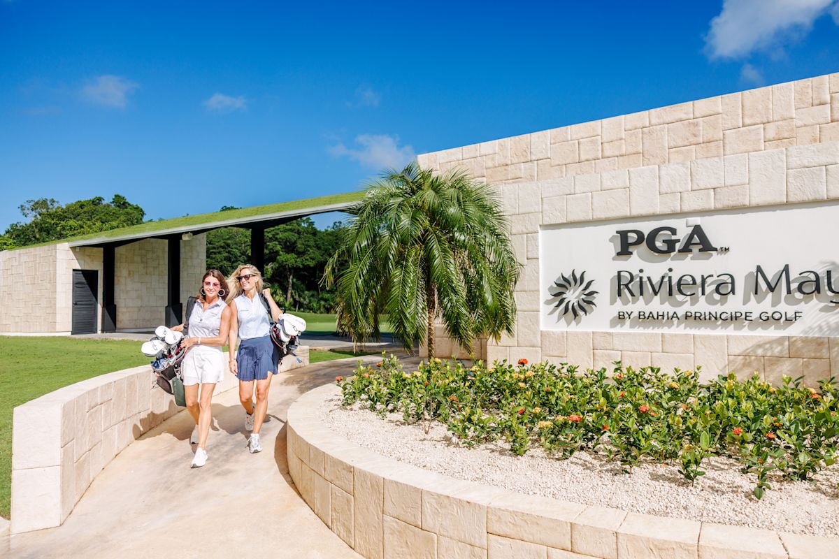 Două femei merg pe jos la intrarea pe PGA Riviera Maya de Bahia Principe Golf