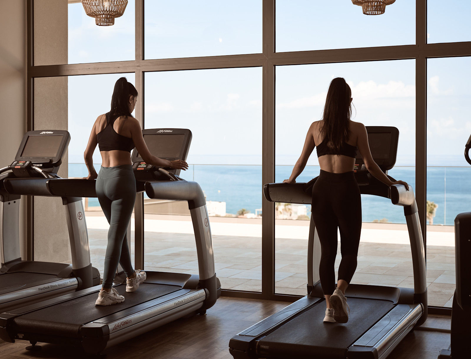 Women on Treadmills in Fitness Center with Beach View