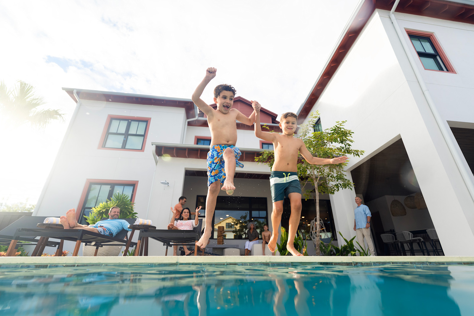 Two boys in trunks preparing to jump into outdoor pool