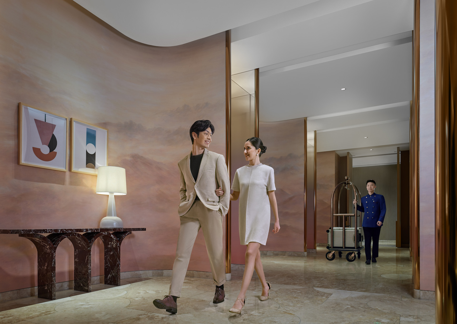 Man and woman walking through hotel hallway with staff member behind