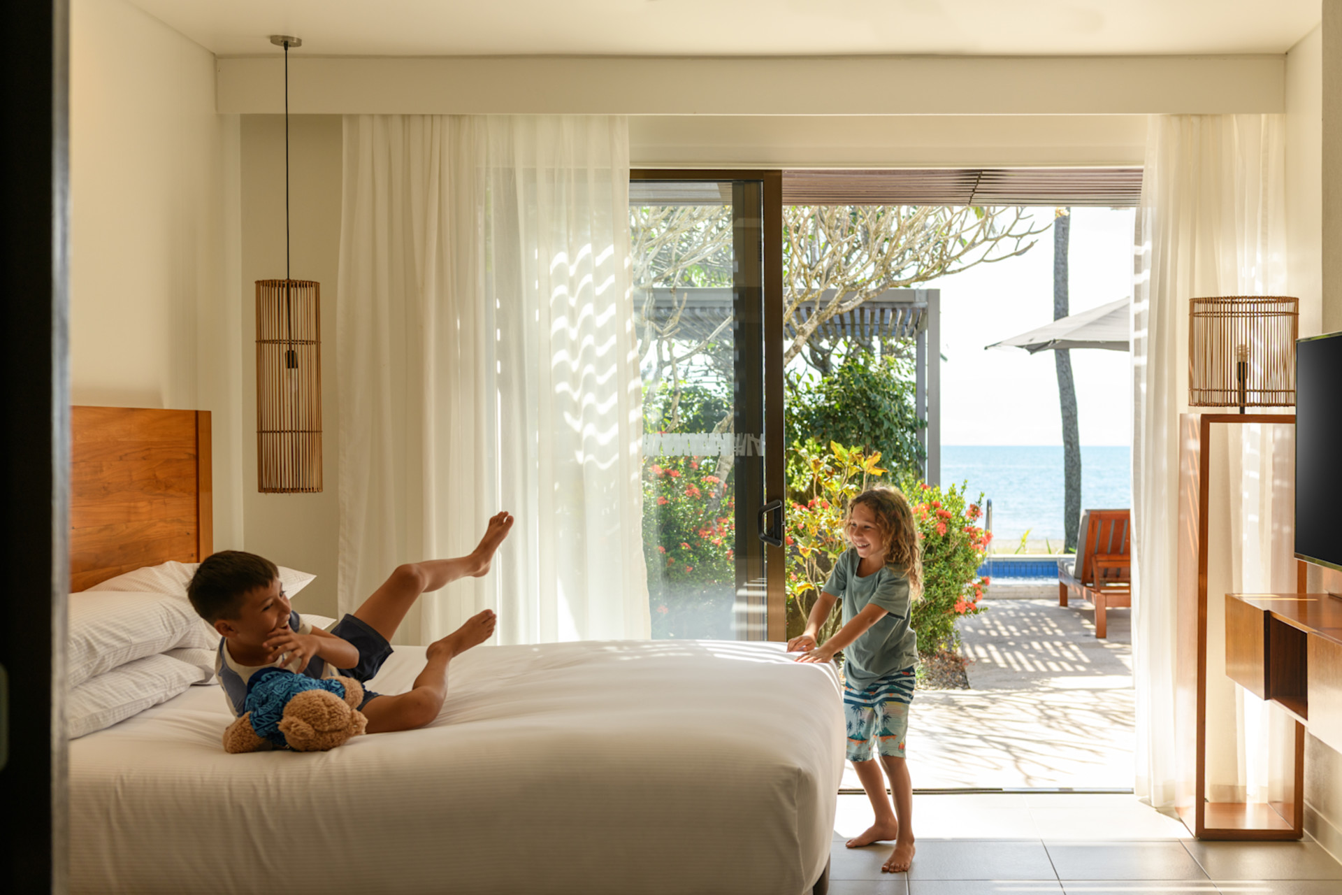 A boy and girl jumping on the bed in a guest room.