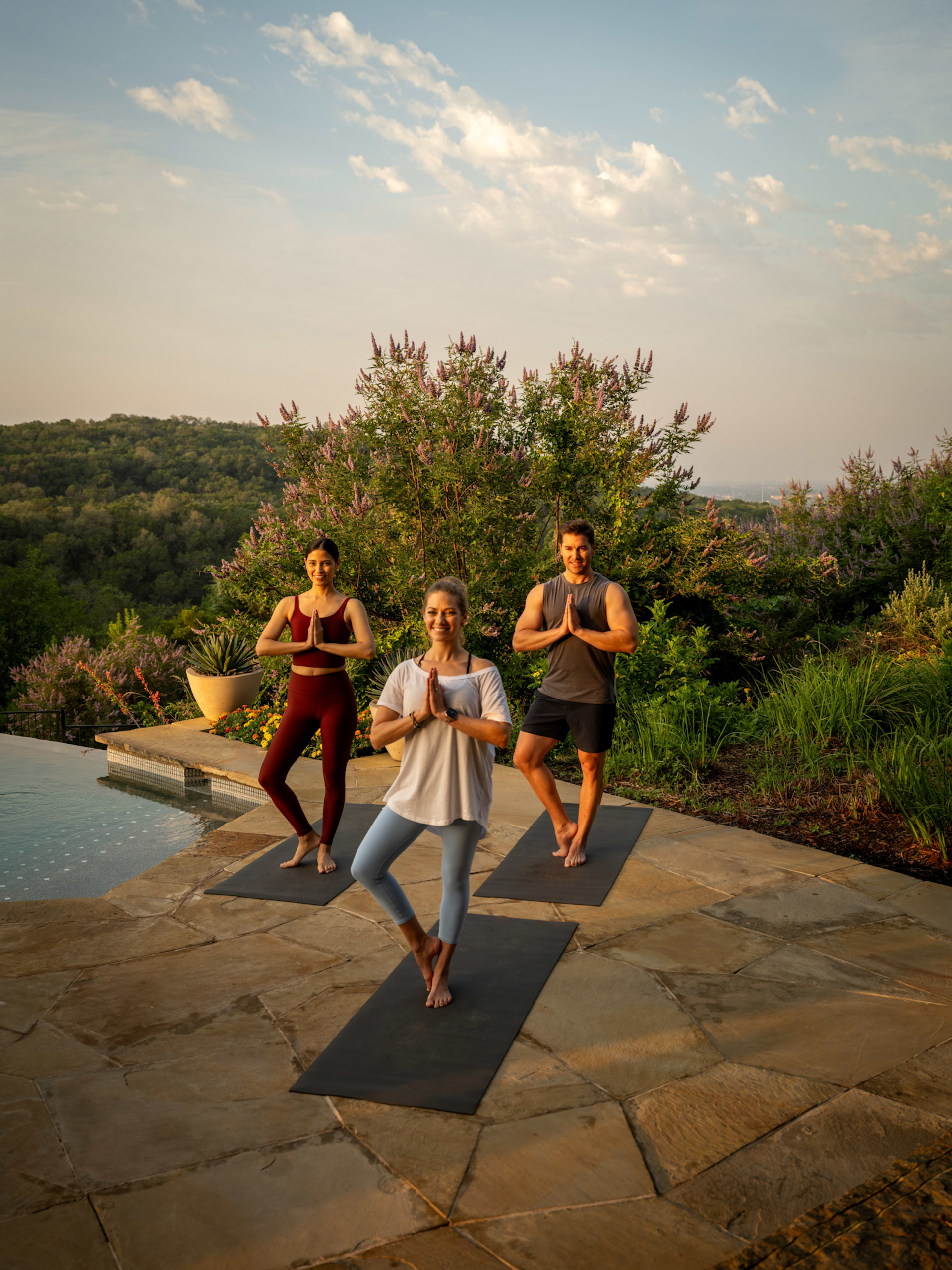 三人在泳池旁的户外进行瑜伽