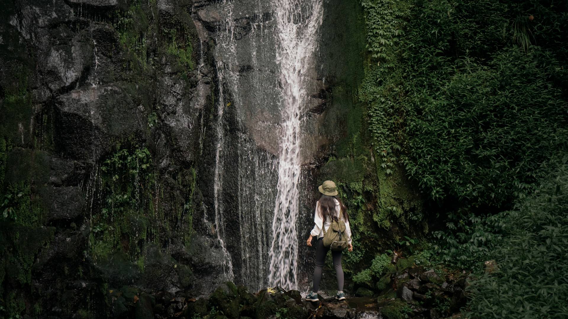 orang berdiri di dekat air terjun