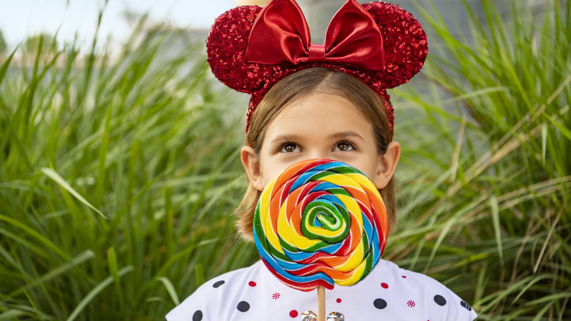 Girl with giant lollypop and red Minnie Mouse ears